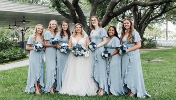 Large wedding party with soft blue bridesmaids gowns and navy blue